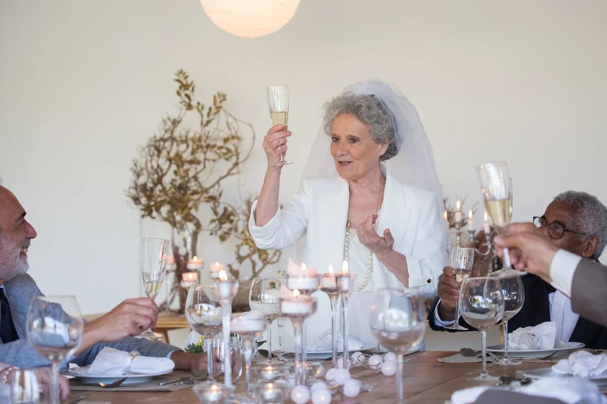 Bryllupsgæster hæver champagneglas til en skål mens nogen holder tale til bryllup
