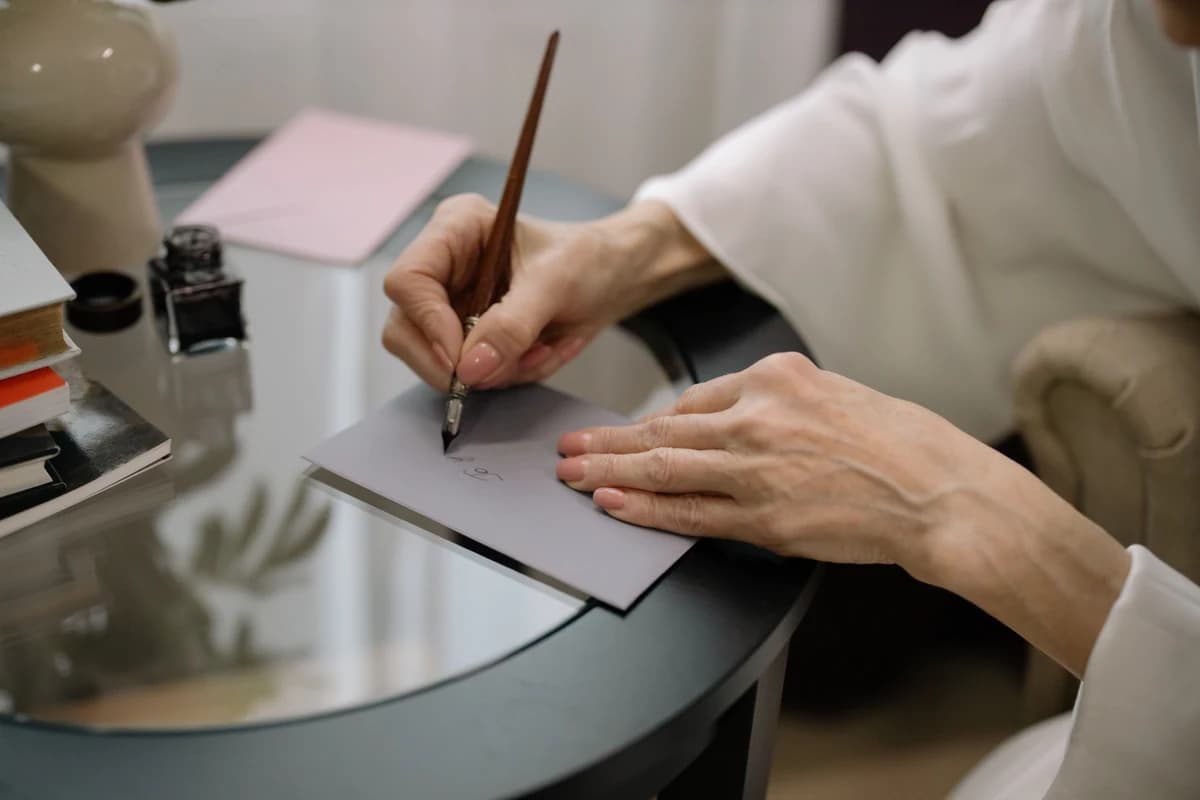 Hånd der skriver en hilsen i et bryllupskort med pen