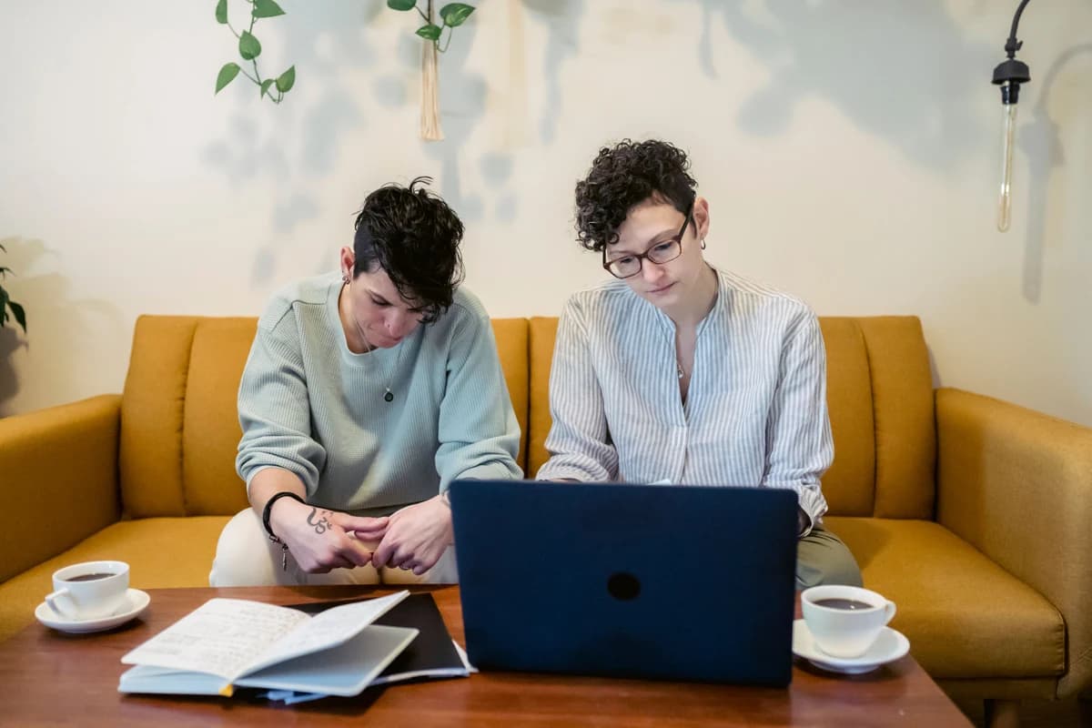 Nyforlovet par starter bryllupsplanleggingen med laptop og blokk hjemme