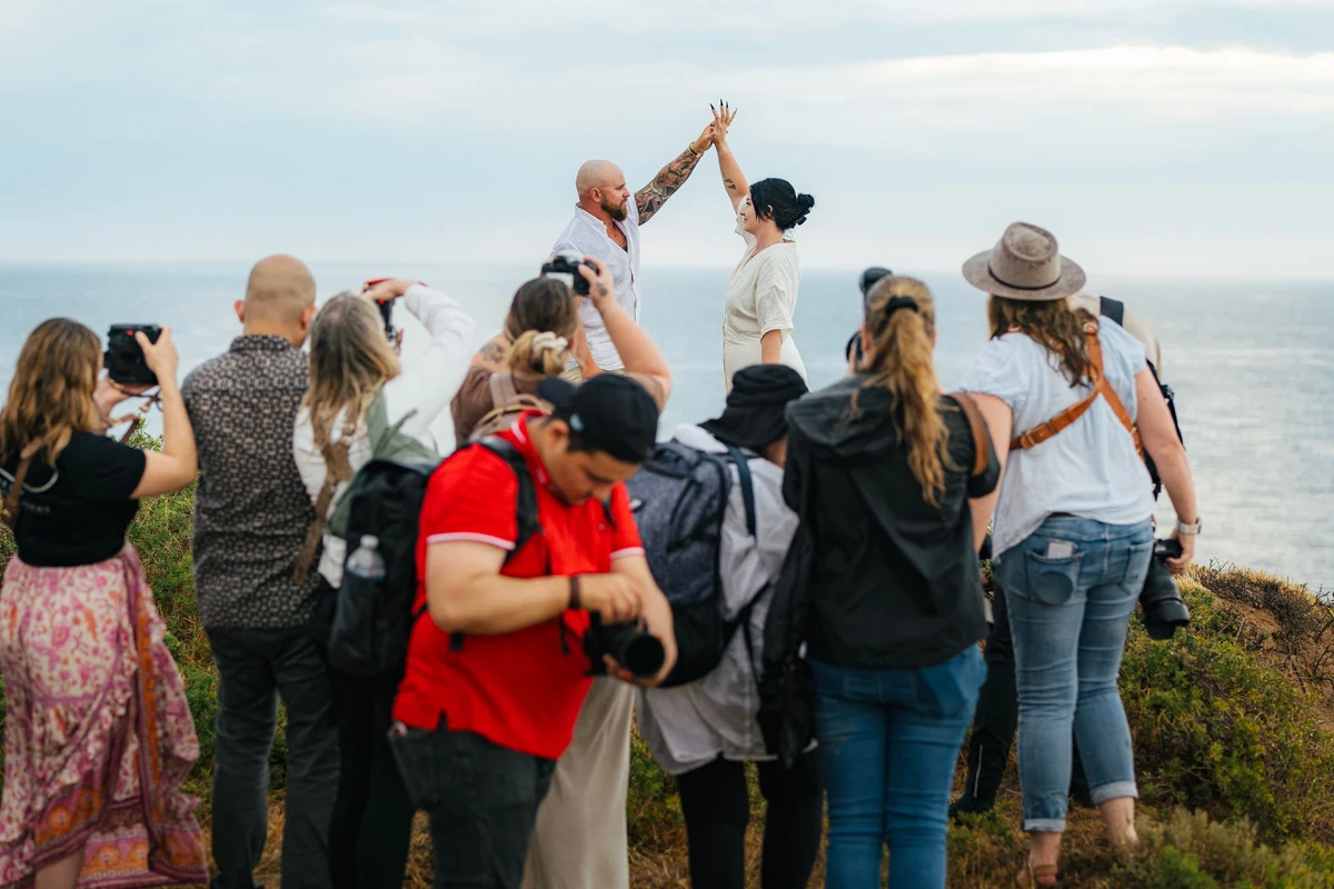 Bröllopsfotograf med kamera fotograferar par utomhus