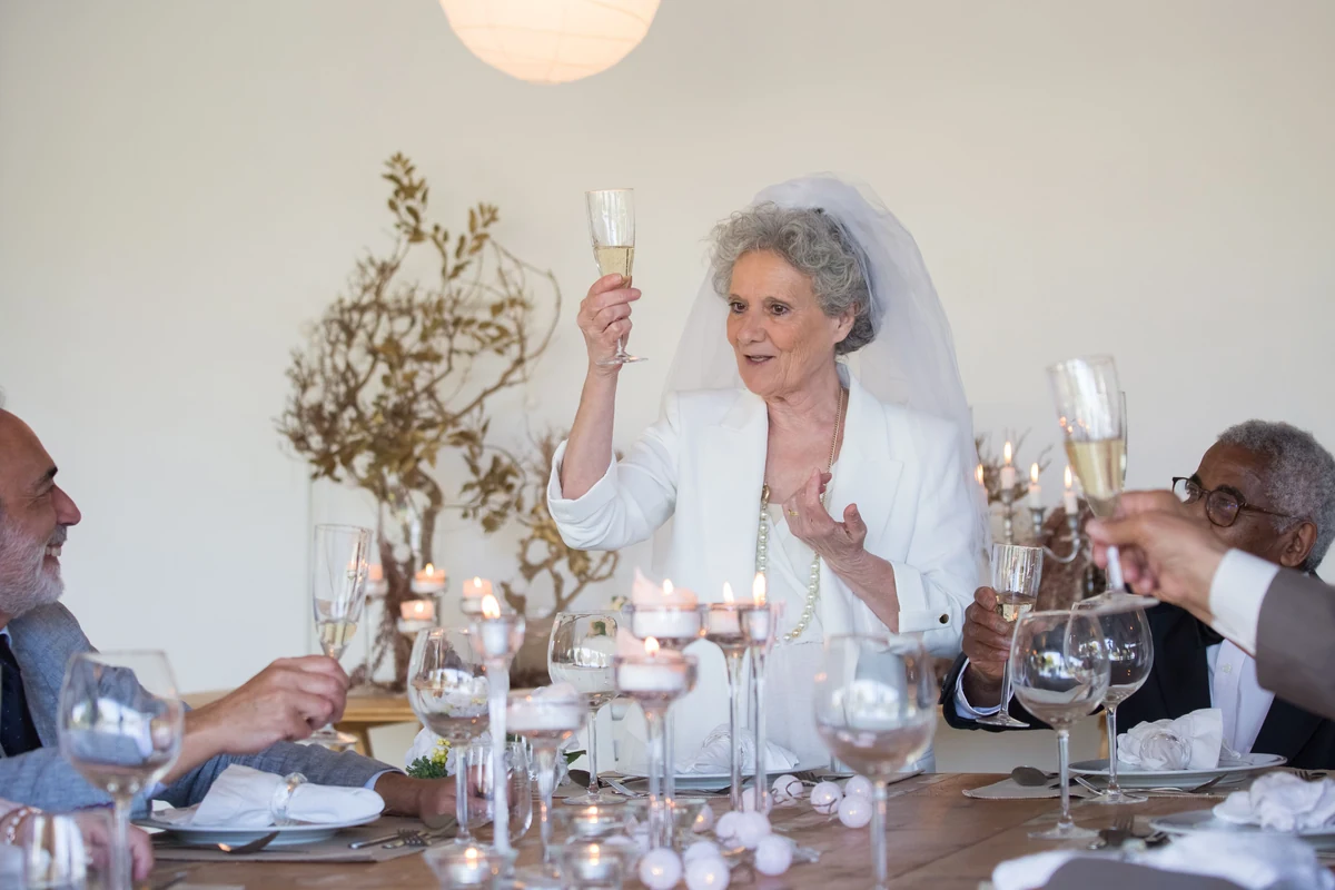 Bryllupsgæster hæver champagneglas til en skål mens nogen holder tale til bryllup