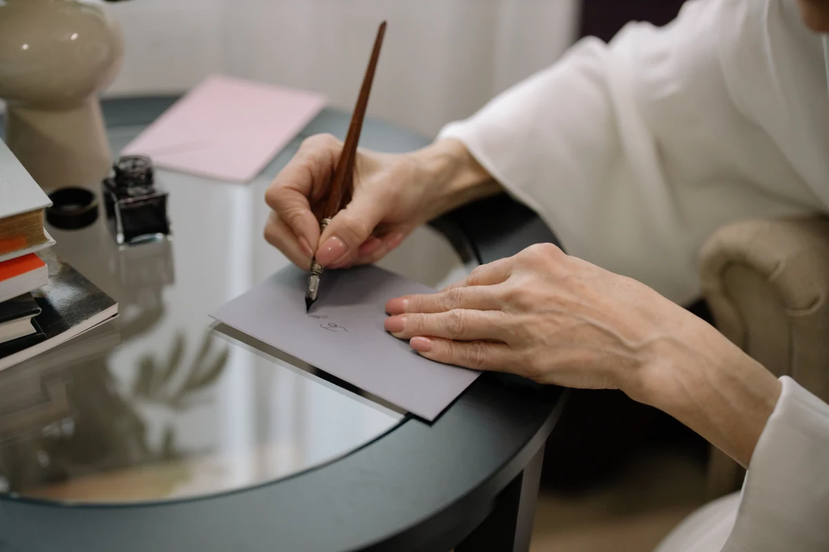 Hånd der skriver en hilsen i et bryllupskort med pen